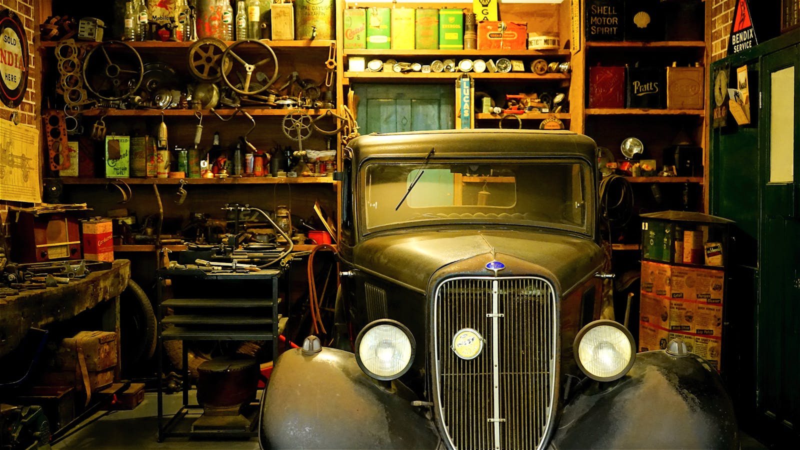 A vintage car surrounded by classic tools and equipment in a workshop setting.