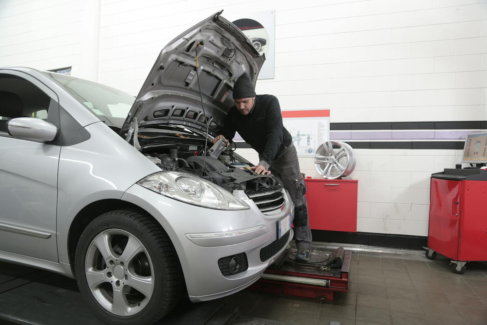 A mechanic checks a car engine for maintenance in a garage setting.